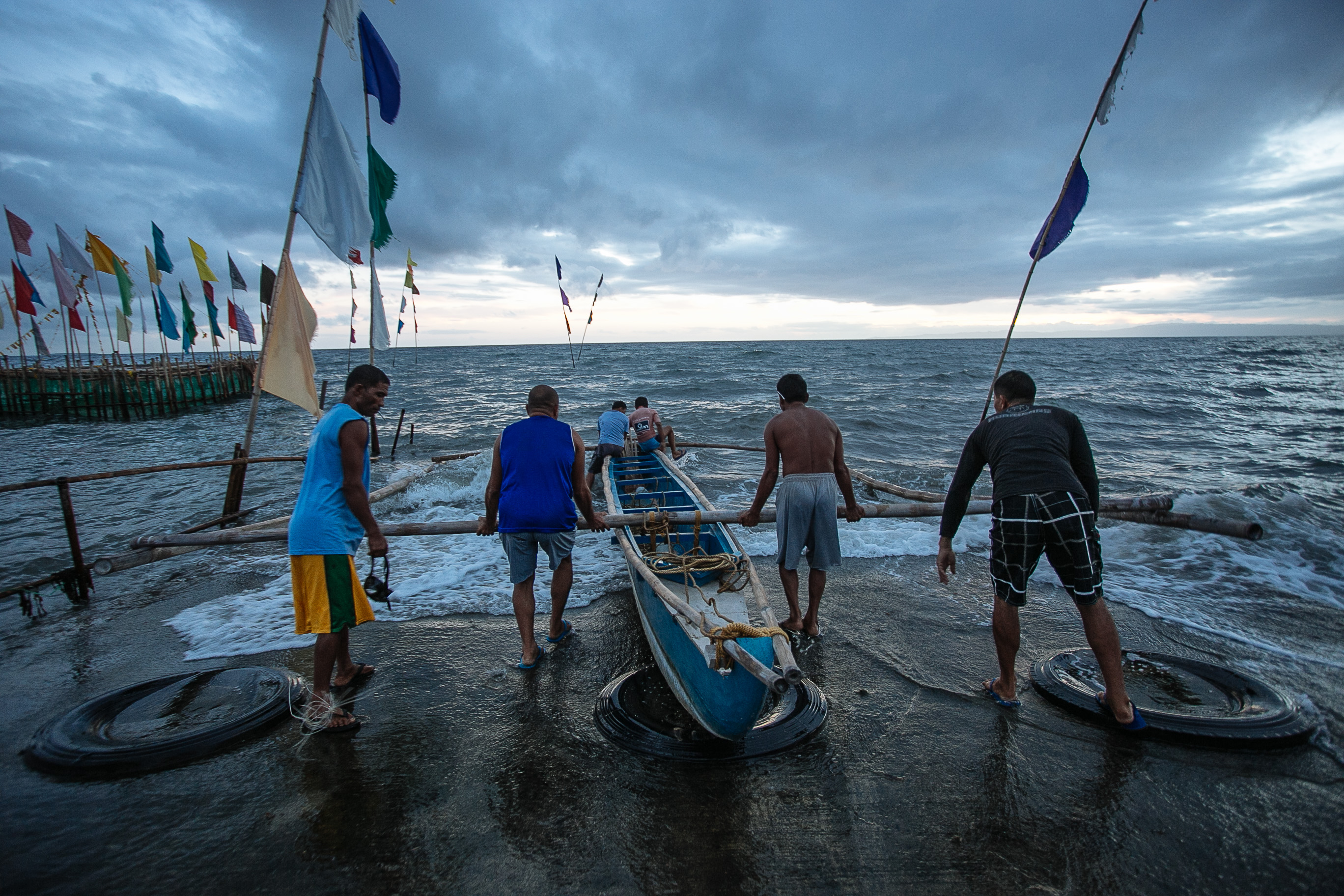 four-person-pushing-boat-off-shore-1390072