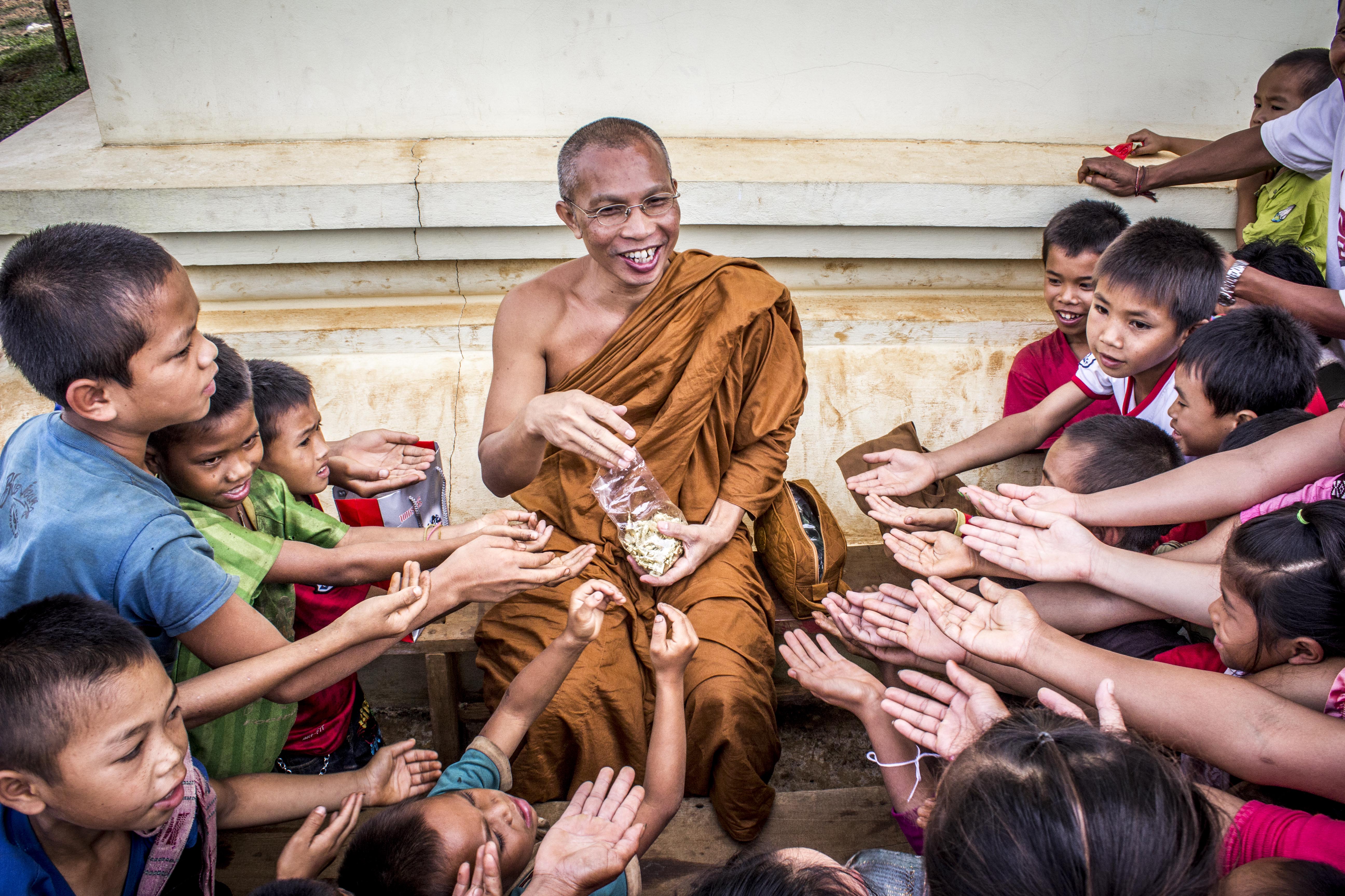 man-in-monk-dress-between-group-of-children-933620